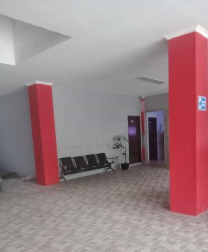 巴厘巴板HER MANDIRI GUEST HOUSE的建筑里一间设有红色柱子和椅子的房间