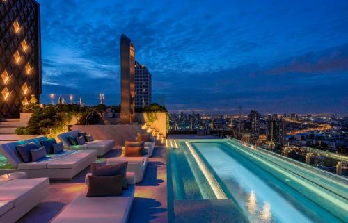 曼谷 曼谷素坤逸怡思得酒店的夜间在建筑物屋顶上的游泳池
