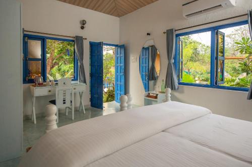 卡纳科纳One At Goa的卧室配有白色的床、书桌和窗户。