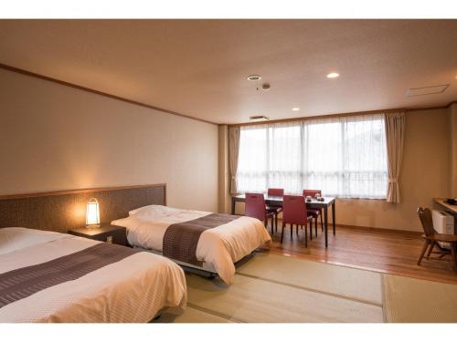 那须盐原市Kouunsou的酒店客房带两张床和一张桌子以及椅子。