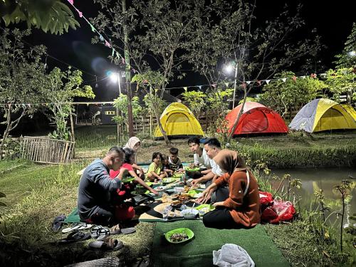 MidangMontong Raden camping ground的一群人坐在帐篷前的野餐桌旁