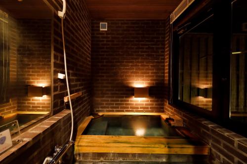 南阿苏村科诺玛玛日式旅馆的砖墙客房内的浴缸