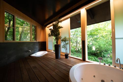山形市ユニテ蔵王ジョーニダ リゾート的一间带两个盥洗盆和浴缸的浴室以及窗户。