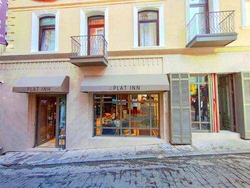 伊斯坦布尔Plat Inn Hotel Taksim的建筑前方的商店,设有窗户和阳台