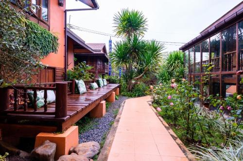 Ban Pa Sangบ้านยุ้งฮีลล์รีสอร์ท Baan Yung Hill Resort的一个带木凳和一些植物的花园