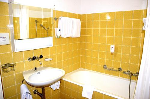 圣莫里茨Hotel Salastrains的浴室配有盥洗盆和浴缸。