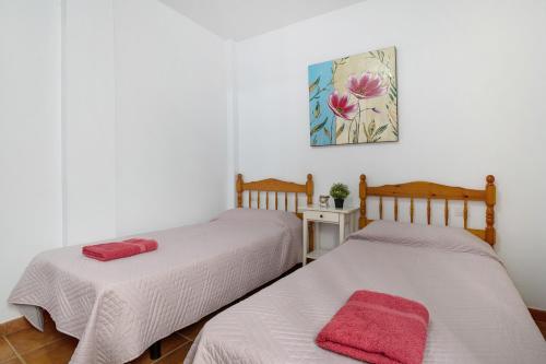 塞博河畔卡莱塔Apartamento Callao, La Graciosa的配有白色墙壁和红色毛巾的客房内的两张床