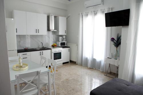 纳夫普利翁Didis Place Nafplio的厨房配有白色橱柜和桌椅