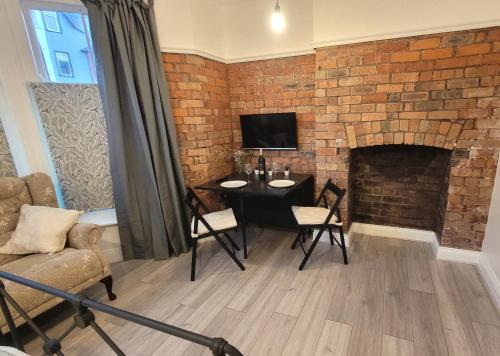 兰德林多德威尔斯Sunnyside Studio Apartment的客厅配有桌子和砖墙