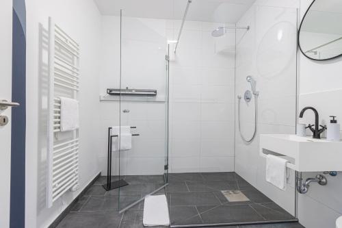 比勒费尔德zzzpace Smart-Hotel Bielefeld Zentrum的带淋浴和盥洗盆的白色浴室