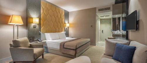 凯里尼亚Elexus Hotel Resort & Spa & Casino的酒店客房配有一张床、一张沙发和椅子。
