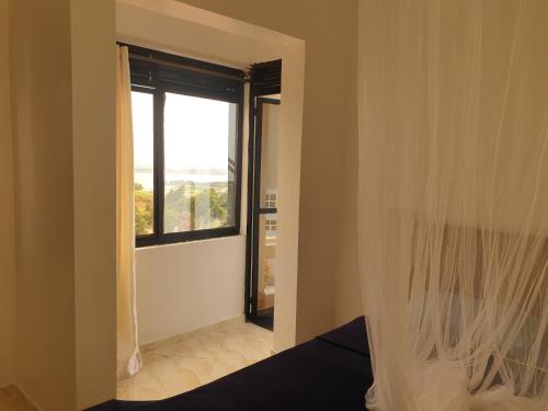 KigoRosa negra kampala的一间卧室设有窗户和一张带窗帘的床