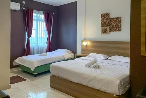 丹戎槟榔RedDoorz Syariah @ Jl D I Panjaitan Batu 7 Tanjung Pinang的酒店客房设有两张床和窗户。