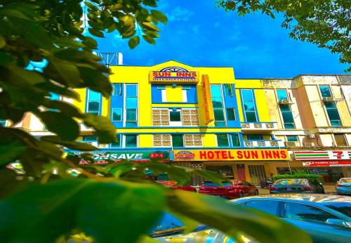 吉隆坡Sun Inns Hotel Kepong near Hospital Sungai Buloh的一座黄色的建筑,汽车停在停车场