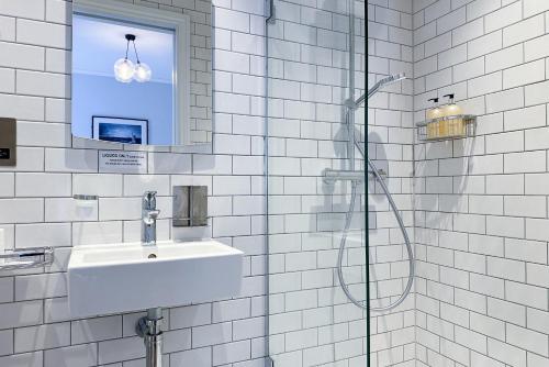 伦敦THE KNIGHT OF NOTTINGHILL的白色瓷砖浴室设有水槽和淋浴