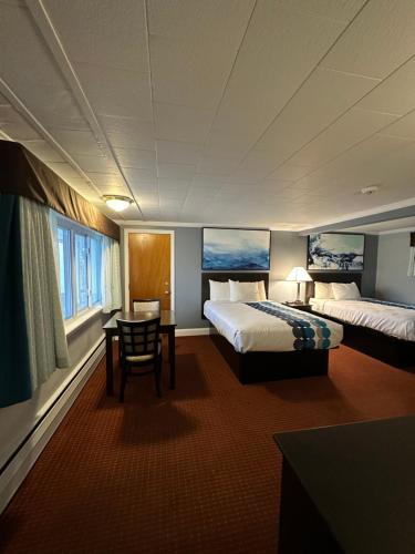 奥尔良Rodeway Inn Orleans - Cape Cod的酒店客房设有两张床、一张桌子和一张桌子。
