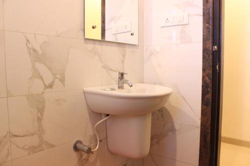 舍地Hotel Sai Ramanand的浴室设有白色水槽和镜子
