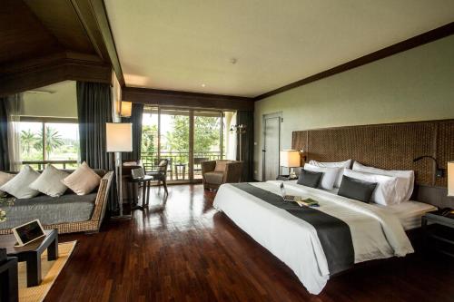 尖竹汶Maneechan Resort - SHA Extra Plus的酒店客房设有一张大床和一张沙发。