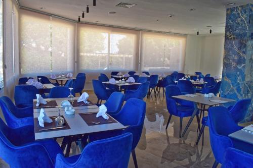 塔巴卡corail royal hotel的一间配备有蓝色椅子和桌子的用餐室