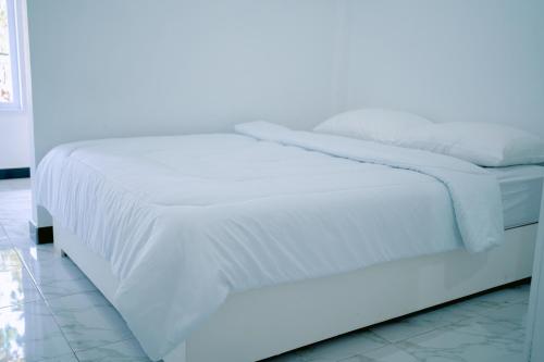 纳闽巴霍Getrudis Guesthouse的白色的床、白色床单和枕头