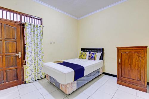 普兰巴南SPOT ON 93007 Guest House Lestari的一间小卧室,配有一张床和一扇木门