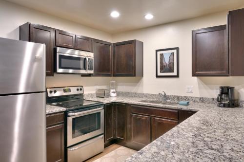 摩押2G New Moab RedCliff Condo, Pool & Hot Tub的厨房配有木制橱柜和不锈钢冰箱。