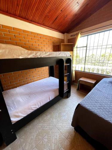 ChachagüíHermosa y lujosa cabaña familiar的一间卧室设有两张双层床和一扇窗户。