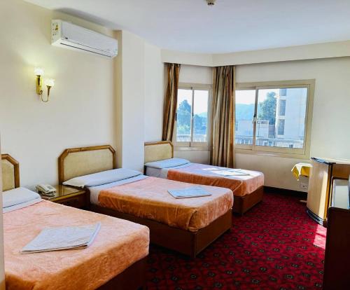 卢克索Queens Valley Hotel的酒店客房设有三张床和窗户。