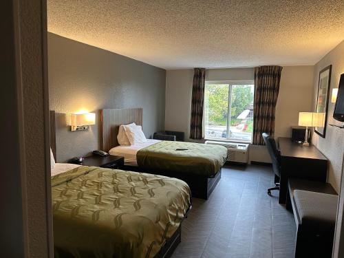 印第安纳波利斯BlissPoint Inn Northwest Indianapolis的酒店客房设有两张床、一张书桌和一个窗户。
