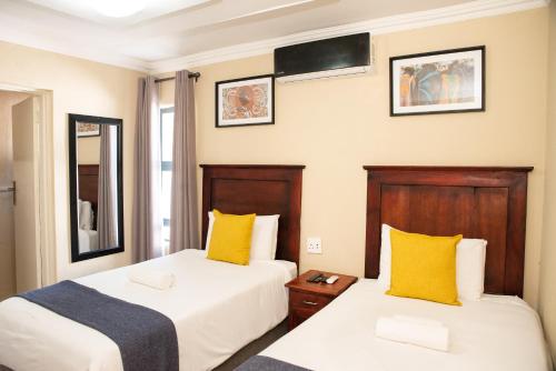 波罗瓜尼M n M Guesthouse Polokwane Central的配有黄色枕头的酒店客房的两张床