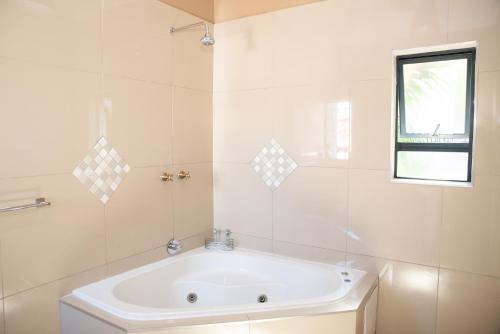 波罗瓜尼M n M Guesthouse Polokwane Central的白色的浴室设有浴缸和窗户。