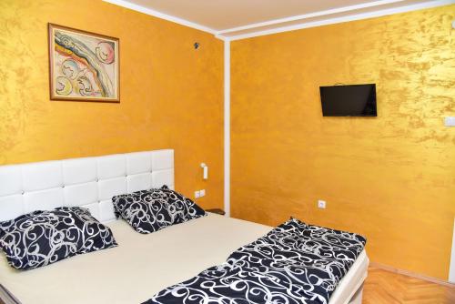 巴尼亚卢卡Goldi apartman的一间卧室设有两张床,墙上配有电视。