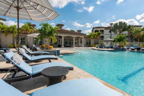 奥兰多Luxury Family Resort Styled Apartment Near Disney的房屋旁的游泳池配有椅子和遮阳伞