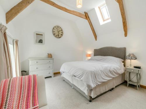 Saint Just in RoselandMyrtle Cottage的卧室配有一张床,墙上挂着一个钟