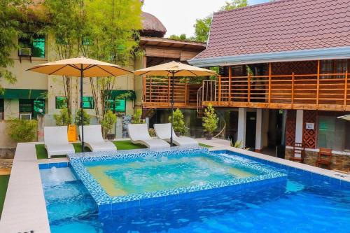 邦劳Ananda Resort的一座带椅子和遮阳伞的游泳池位于一座建筑旁边