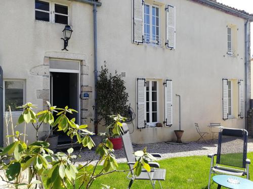 Saint-Amand-sur-Sèvrele gîte du fou logement 8 pers 13mn puy du fou的一座带椅子的院子的房子和一座建筑