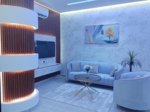 哈费尔巴廷العلي للشقق المخدومة Alalihotel的客厅配有蓝色的沙发和电视