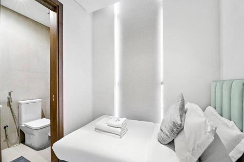迪拜StoneTree - Anwa By Omniyat 2BR - Luxury Apartment的白色卧室配有床和镜子