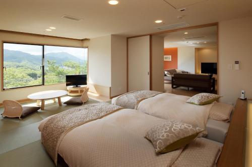 仙台仙台秋保温泉 篝火の湯 緑水亭的一间带两张床的卧室和一间享有美景的客厅