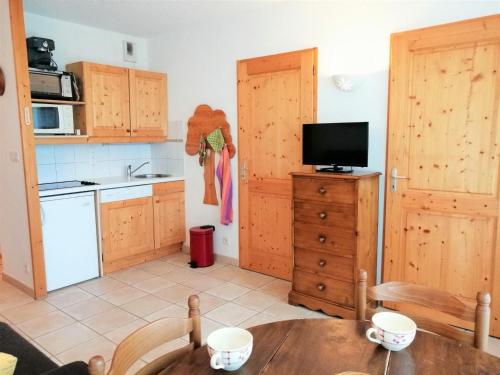 莫里永Appartement Morillon 1100, 3 pièces, 6 personnes - FR-1-412-17的厨房配有木制橱柜、桌子和电视。