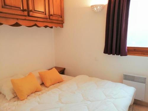 莫里永Appartement Morillon 1100, 3 pièces, 6 personnes - FR-1-412-17的卧室配有白色床和2个橙色枕头