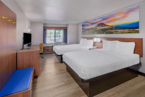 格里利Days Inn & Suites by Wyndham Greeley的酒店客房设有两张床和一台平面电视。