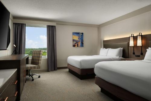 月球乡希尔顿逸林酒店匹兹堡机场店的酒店客房设有两张床、一张书桌和一个窗户。