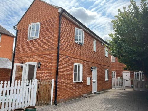 亨利昂泰晤士Mews house in the centre of Henley-on-Thames的白色栅栏的红砖建筑