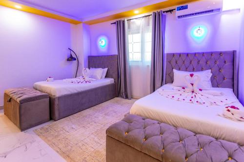 南威Canary Nungwi Hotel & Free SPA的紫色的客房配有两张床和一张沙发