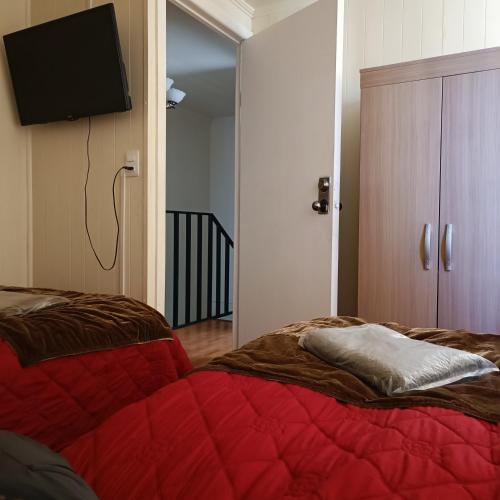 伊基克Casa dos dormitorios的一间卧室配有红色的床和一台平面电视