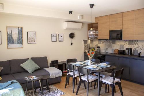 哈拉霍夫ENJOYHARRACHOV - Atraktivní slunný klimatizovaný apartmán 14 v centru Harrachova se saunou, parkováním, Wifi-WLAN, SAT, herní konzolí, PC s win 10, Netflix zdarma a možností dobíjení auta s jedinečným výhledem na Čertovu horu se skokanskými můstky的客厅以及带桌子和沙发的厨房。