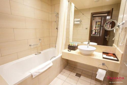 阿布扎比阿布扎比华美达市区酒店的带浴缸、水槽和镜子的浴室