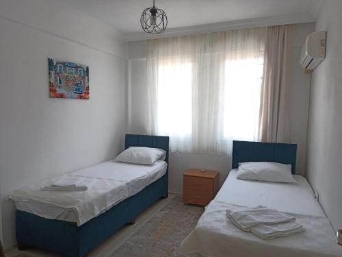 费特希耶2 Yatak Odalı Daire-Fethiye的一间卧室设有两张床和窗户。