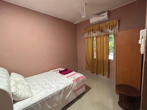 丹那美拉Homestay Taman Hidayah Chawas的一间卧室配有一张床和一个带风扇的窗户。